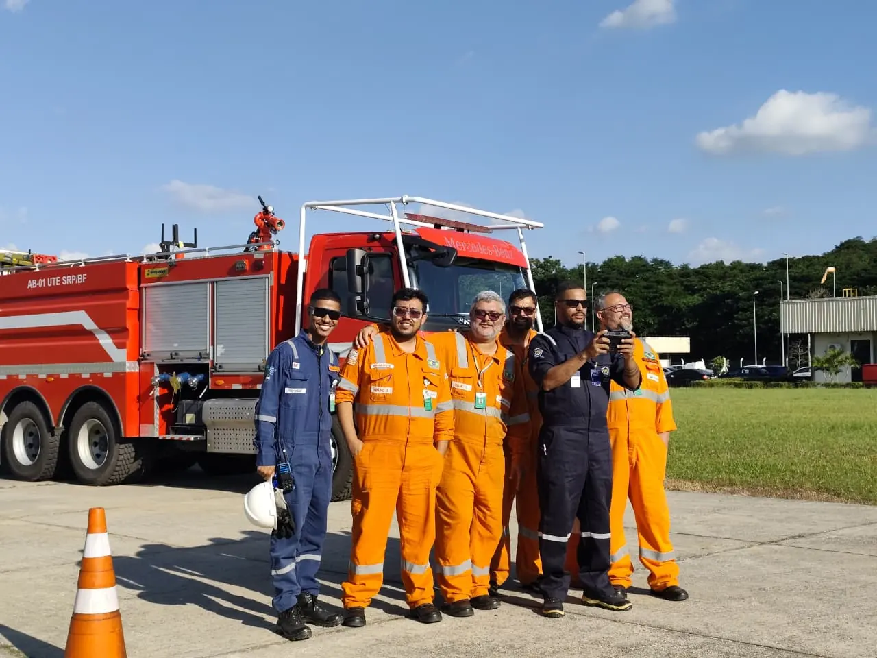 Turma de alunos e instrutores do curso reunida na área externa, ao lado de um caminhão de bombeiros
